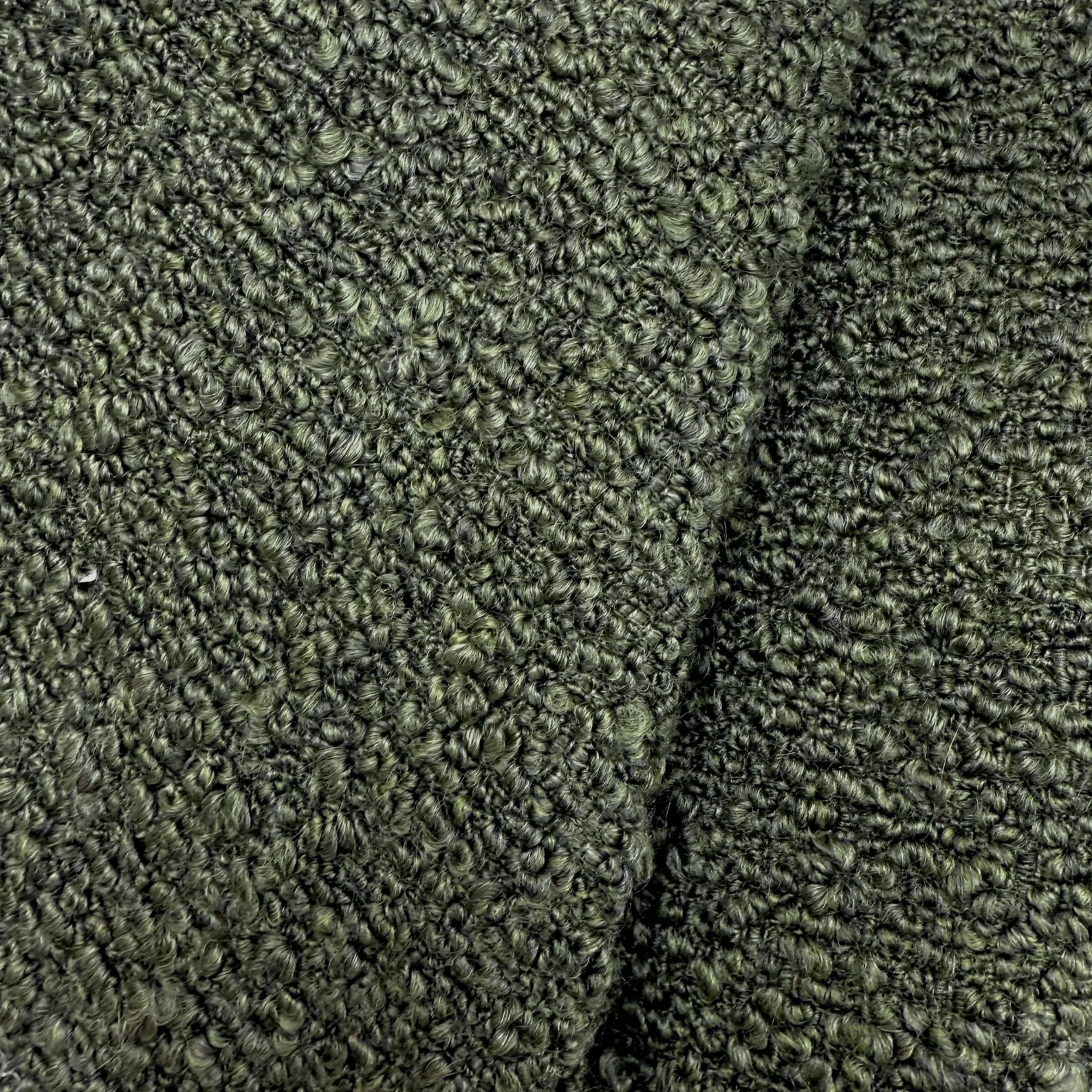 a close-up view of a textured fabric with a dark green or black color. The fabric appears to be made of a tightly woven material, giving it a distinctive and intricate appearance.