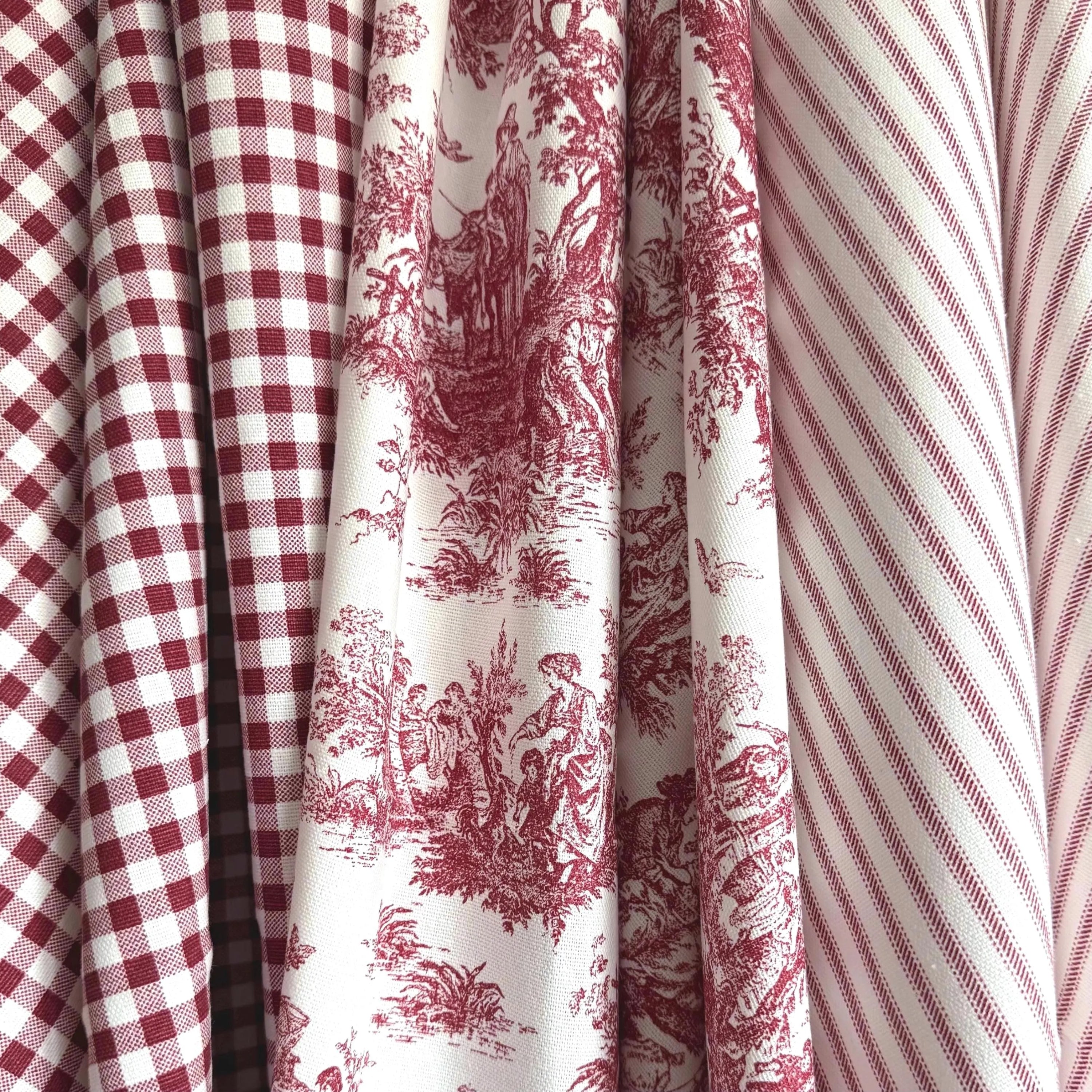 a close-up view of a collection of fabric swatches, including a red and white checkered fabric, a red and white striped fabric, and a red and white floral fabric.