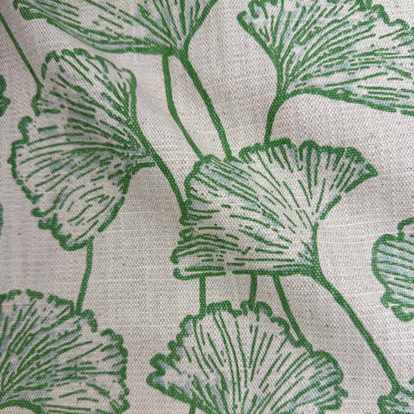 a close-up view of a fabric with a repeating pattern of green leaves or flowers. The pattern is intricate and detailed, with the leaves or flowers appearing to be made of a soft, textured material. The fabric has a white background, which contrasts with the green leaves and makes them stand out. The leaves are arranged in a way that creates a sense of depth and dimension, giving the fabric a three-dimensional appearance.