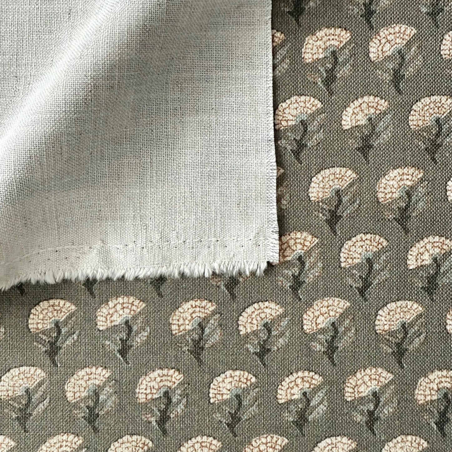 a close-up view of a fabric with a floral pattern, featuring a mix of white and gray colors. The fabric appears to be made of a soft, textured material, possibly cotton or linen. The pattern consists of repeating floral motifs, creating a visually appealing and intricate design.
