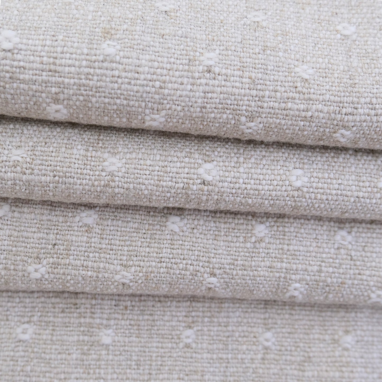 A close-up view of a fabric with a textured, woven pattern in shades of beige and white.