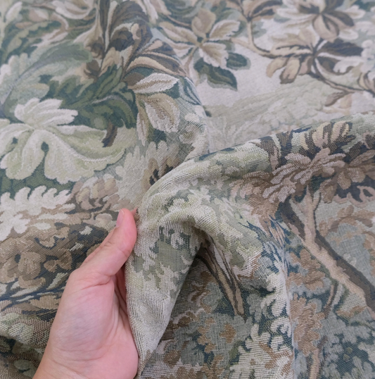 A hand is holding a fabric with a floral pattern, which appears to be a close-up view of the fabric.