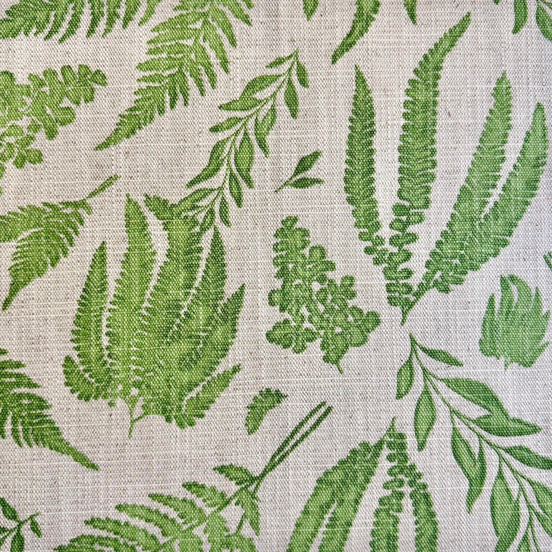 a close-up view of a fabric with a repeating pattern of green fern leaves and other green plant-like leaves. The pattern is intricate and detailed, creating a visually appealing and natural-looking design.
