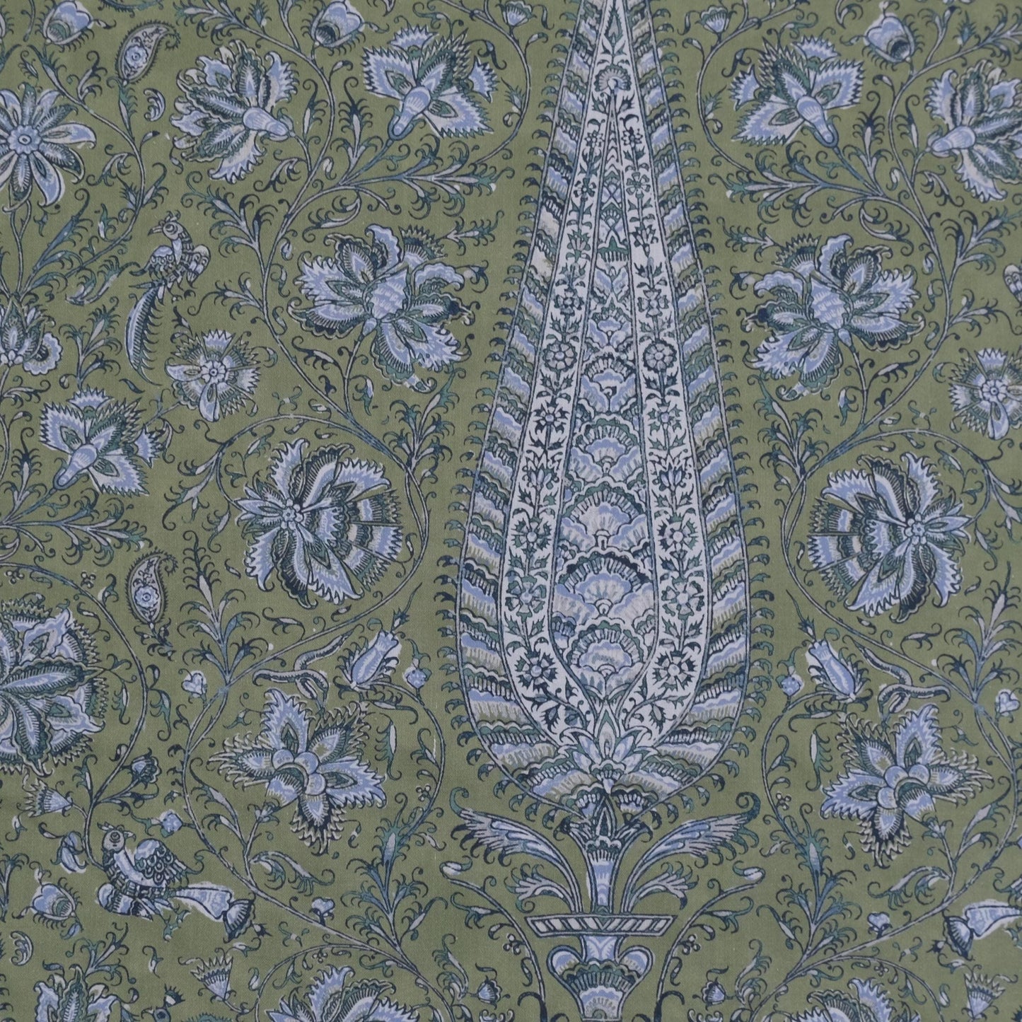 a detailed and intricate paisley pattern with a large central motif surrounded by smaller floral and leaf-like designs in shades of green and blue. The pattern appears to be a textile or wallpaper design, with the central motif being the focal point.
