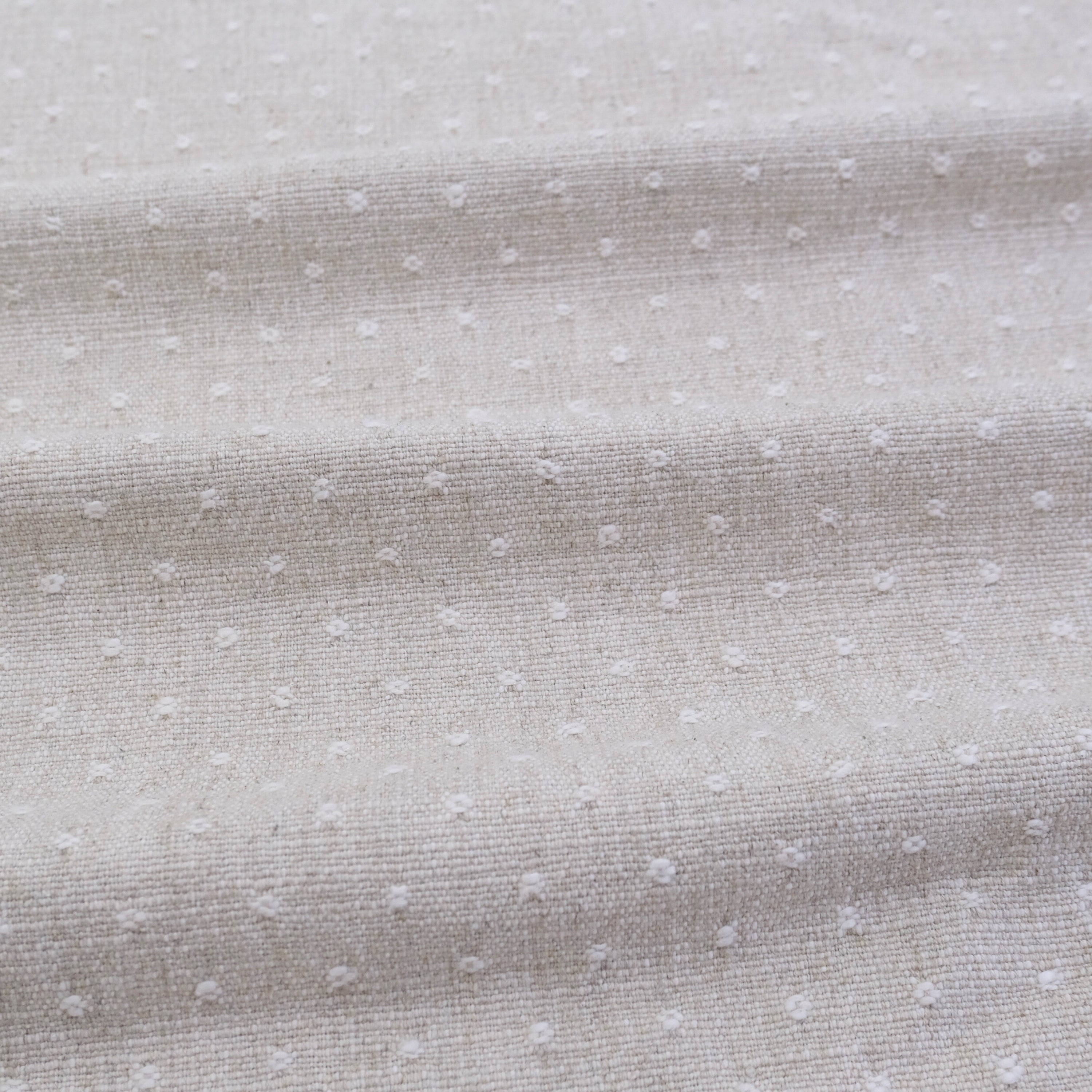 a close-up view of a fabric with small white dots or polka dots, creating a textured and patterned appearance.