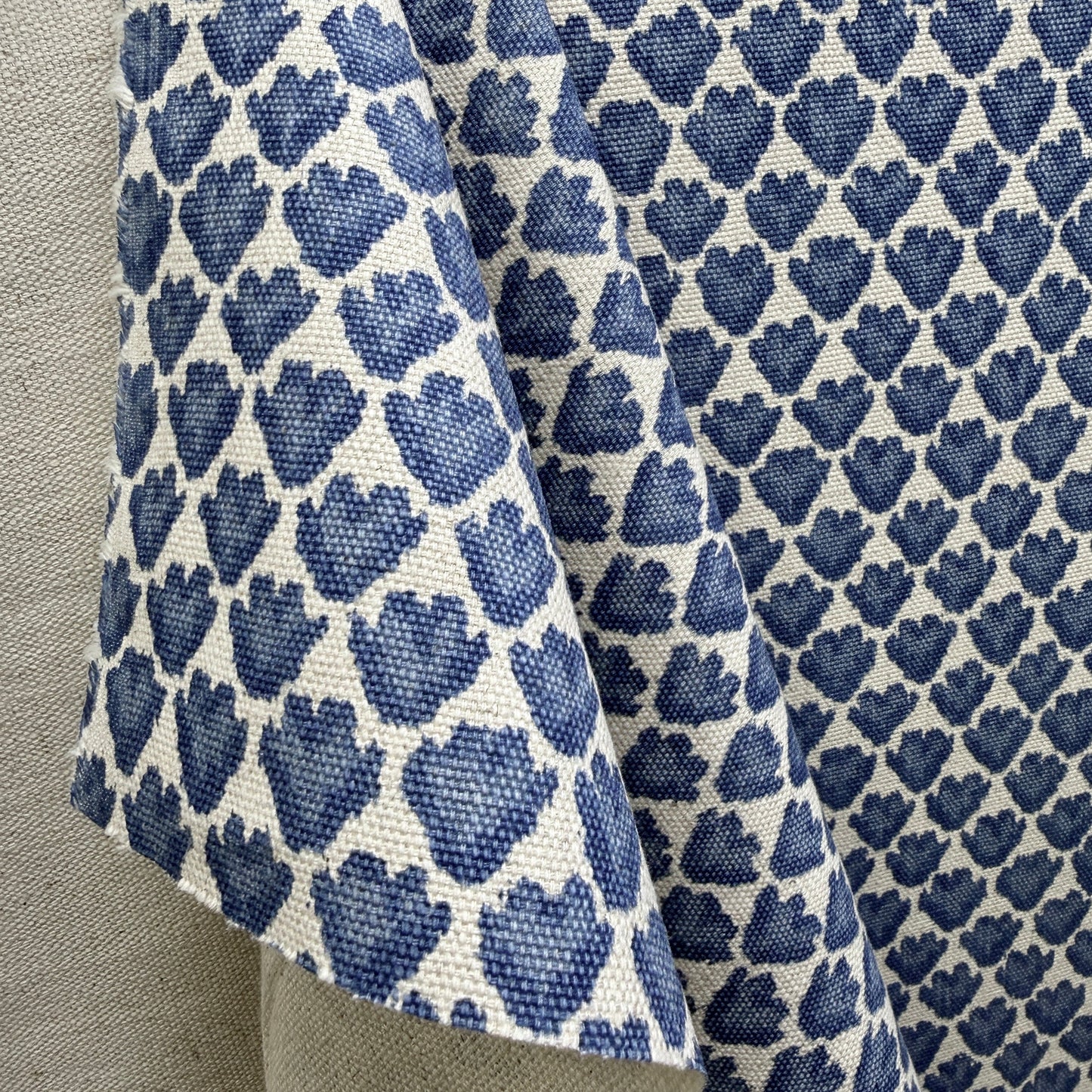Blue and cream geometric floral fabric in soft drape showing repeat pattern scale