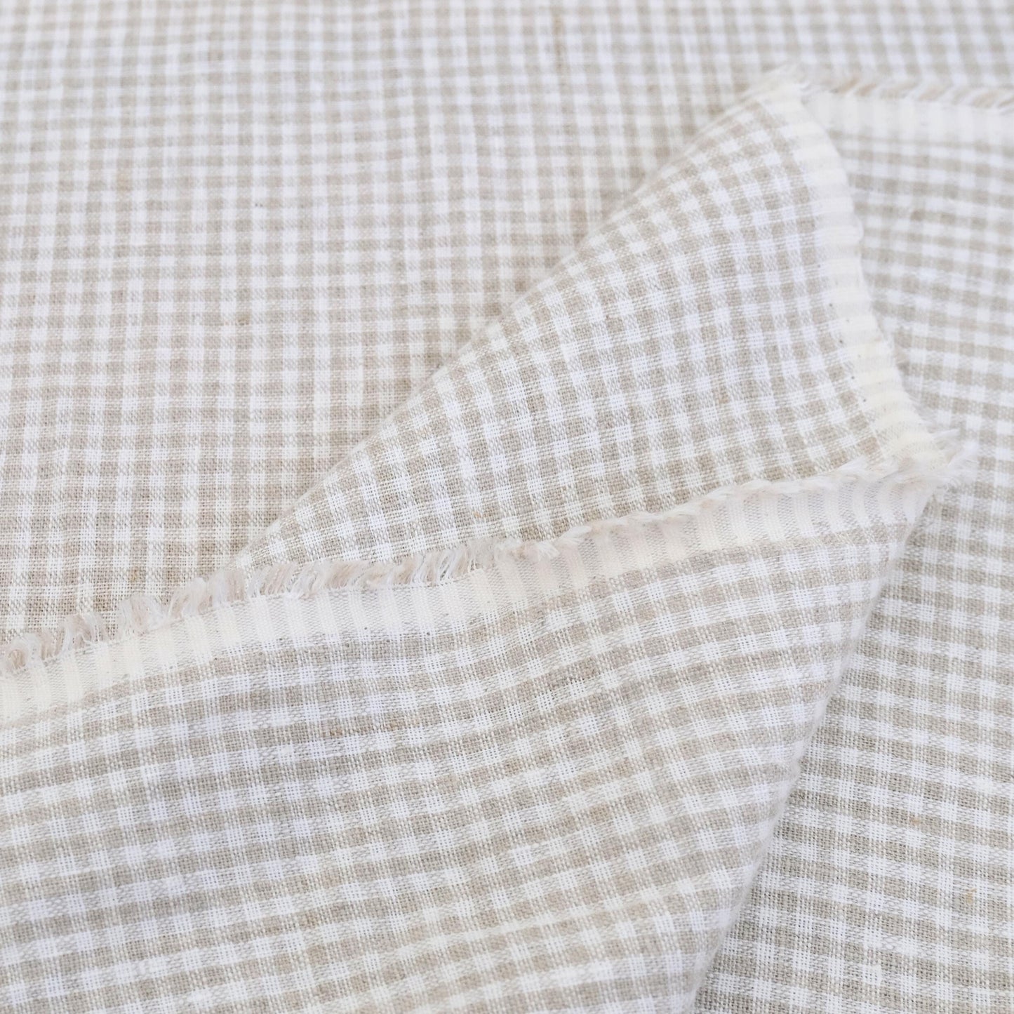 Textured gingham check fabric in beige and white, ideal for cushions and table linens