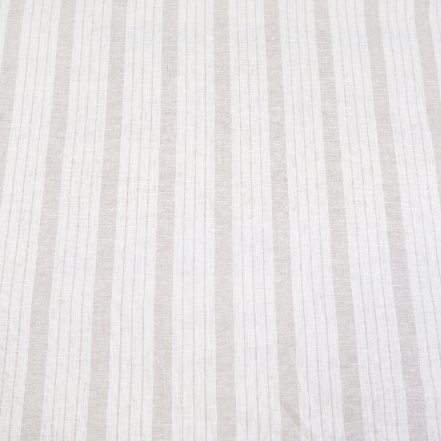 Flat lay of taupe striped linen fabric showing even balanced stripes and neutral color tones. The fabric’s light drape makes it perfect for farmhouse style drapery, rustic table runners, DIY napkins, and cottage-style crafts. This striped linen is a versatile choice for sewing enthusiasts looking to create timeless, minimalist home décor items with natural linen texture and neutral earthy stripes.