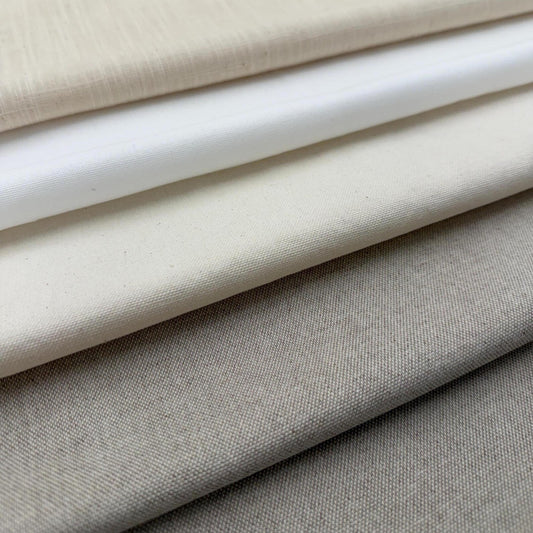 A close-up image of various fabric swatches in shades of beige and white, arranged in a layered fashion.