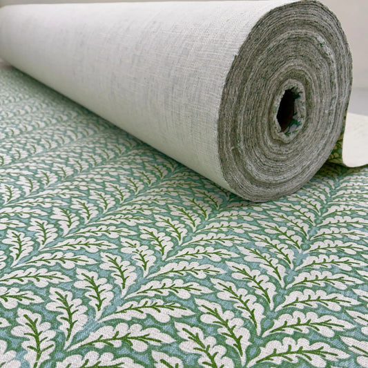 a roll of fabric with a repeating pattern of green leaves on a white background.