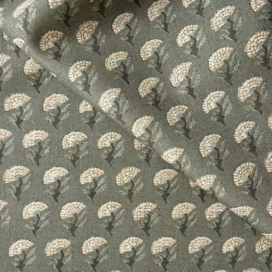 a close-up view of a fabric with a repeating pattern of white flowers or leaves on a dark green background.