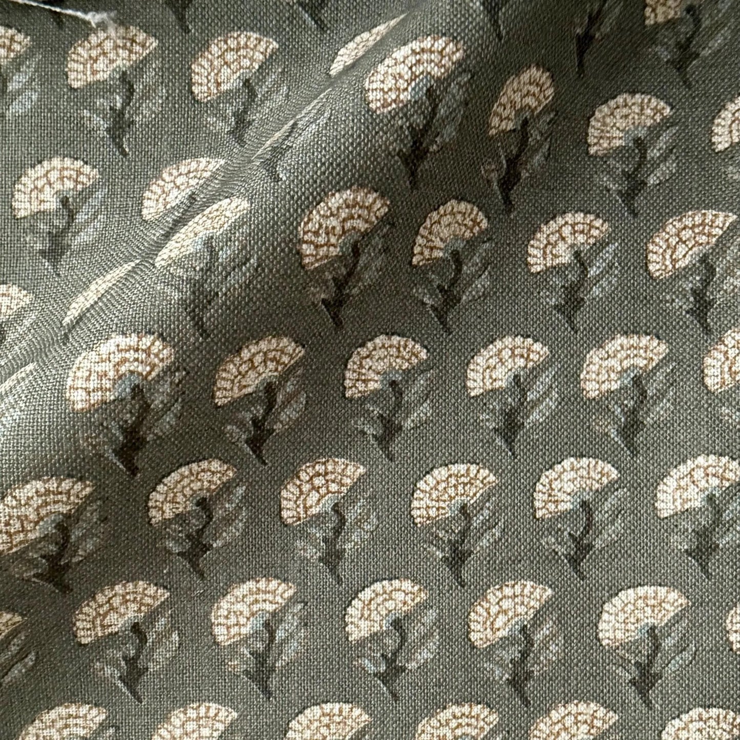 a close-up view of a fabric with a repeating pattern of white flowers or leaves on a dark background.