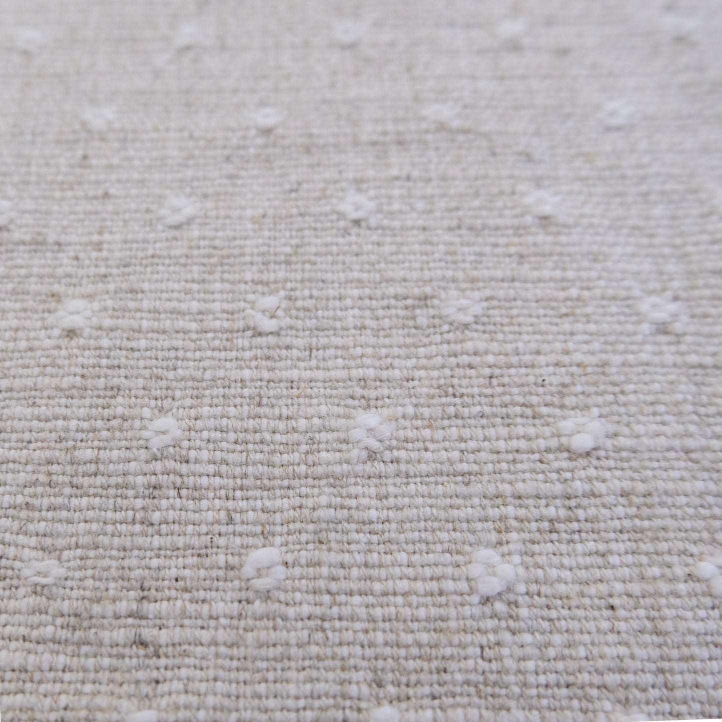 a close-up view of a beige fabric with small white dots or circles scattered across it, creating a textured and patterned appearance.