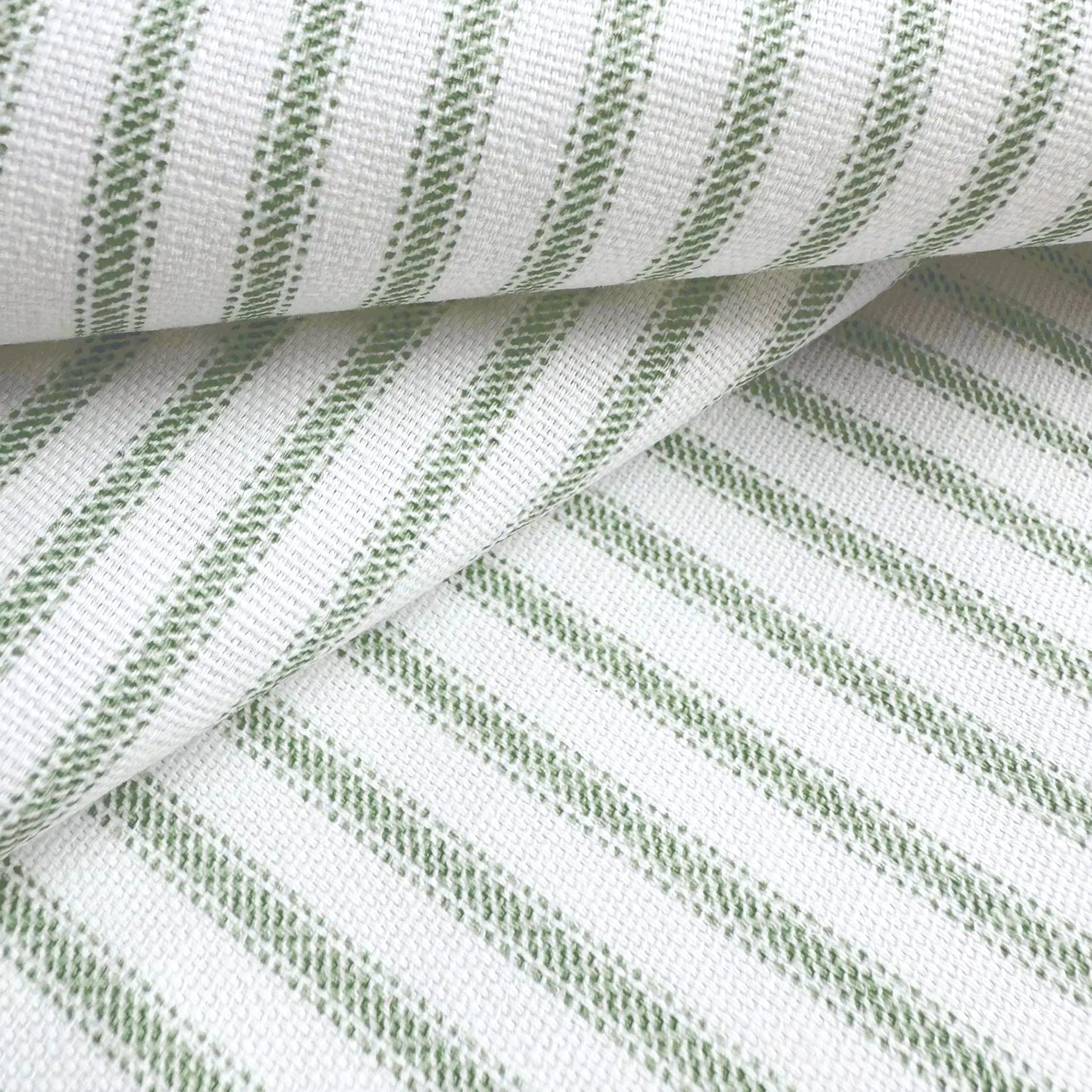 a close-up view of a fabric with a striped pattern in shades of green and white. The fabric appears to be folded or rolled, creating a visually interesting and textured surface.