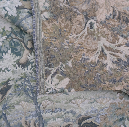 The image is a close-up of a fabric with a floral pattern, featuring a mix of green, blue, and brown colors.