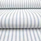 a close-up view of a fabric with a striped pattern in shades of blue and white. The fabric appears to be folded or rolled up, creating a layered effect.