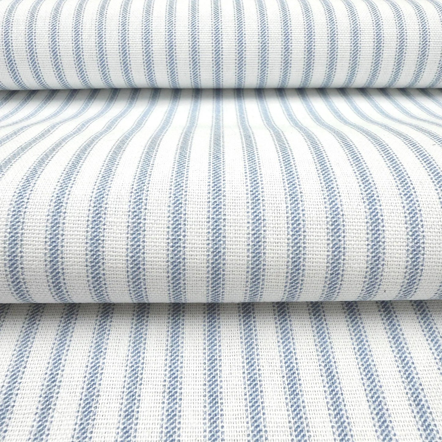 a close-up view of a fabric with a striped pattern in shades of blue and white. The fabric appears to be folded or rolled up, creating a layered effect.