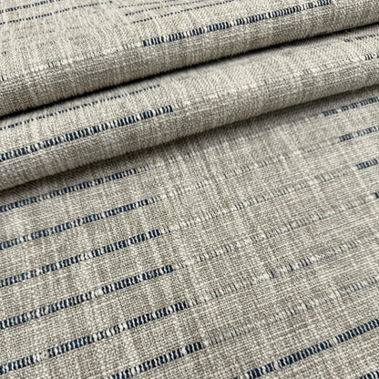 a close-up view of a fabric with a striped pattern in shades of gray and blue. The fabric appears to be folded or rolled, creating a layered effect.