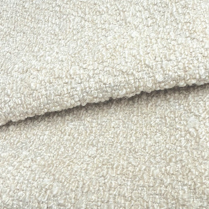 A close-up image of a textured fabric, likely a white or cream-colored material, with a slightly curled or folded appearance.