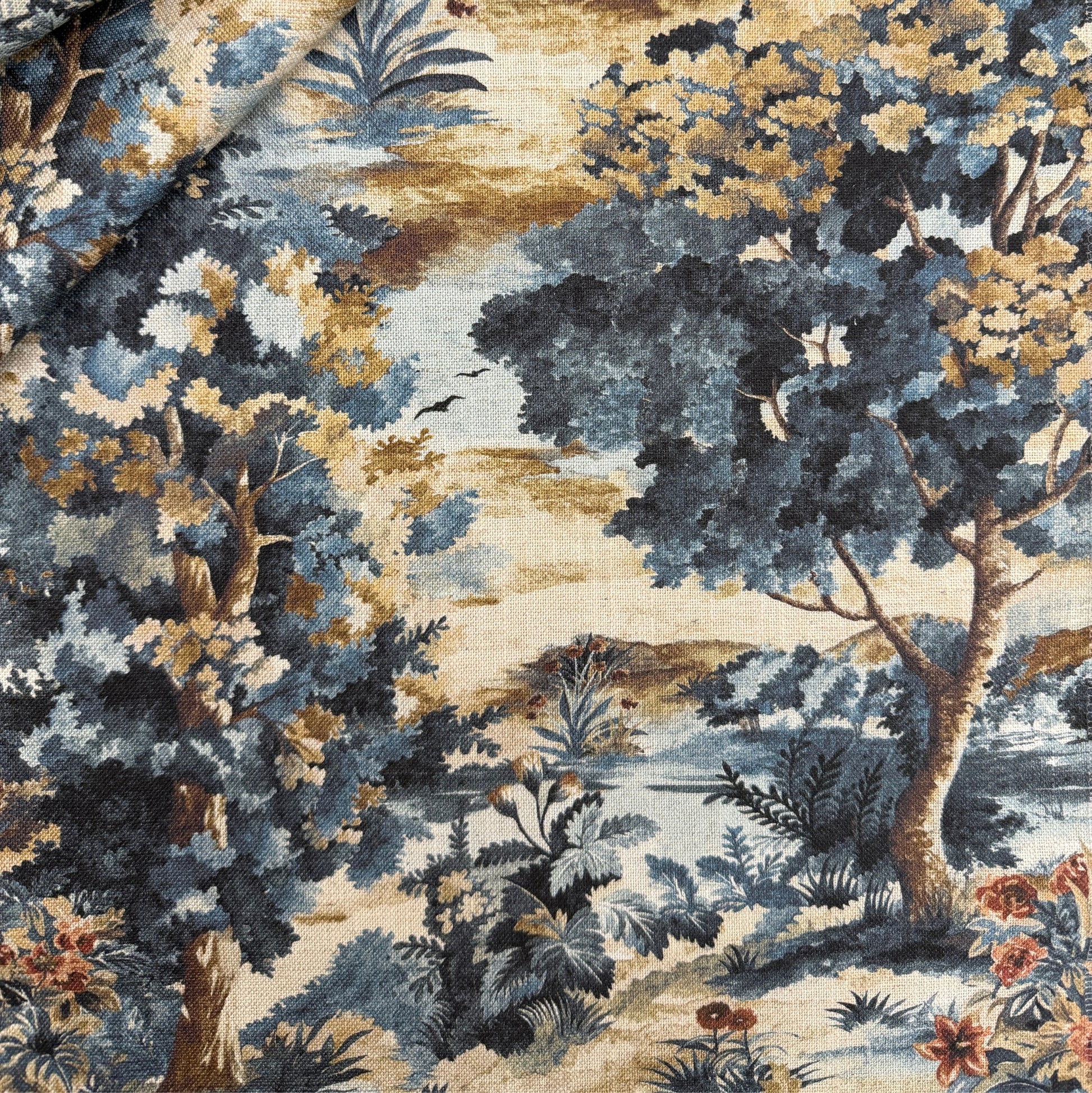 The image is a detailed fabric print featuring a lush, colorful landscape with trees, flowers, and foliage in shades of blue, green, and gold.