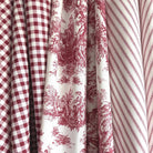 a close-up view of a collection of fabric swatches, including a red and white checkered fabric, a red and white striped fabric, and a red and white floral fabric.