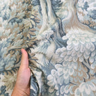 A hand is holding a fabric with a floral pattern, which appears to be a close-up view of the material.