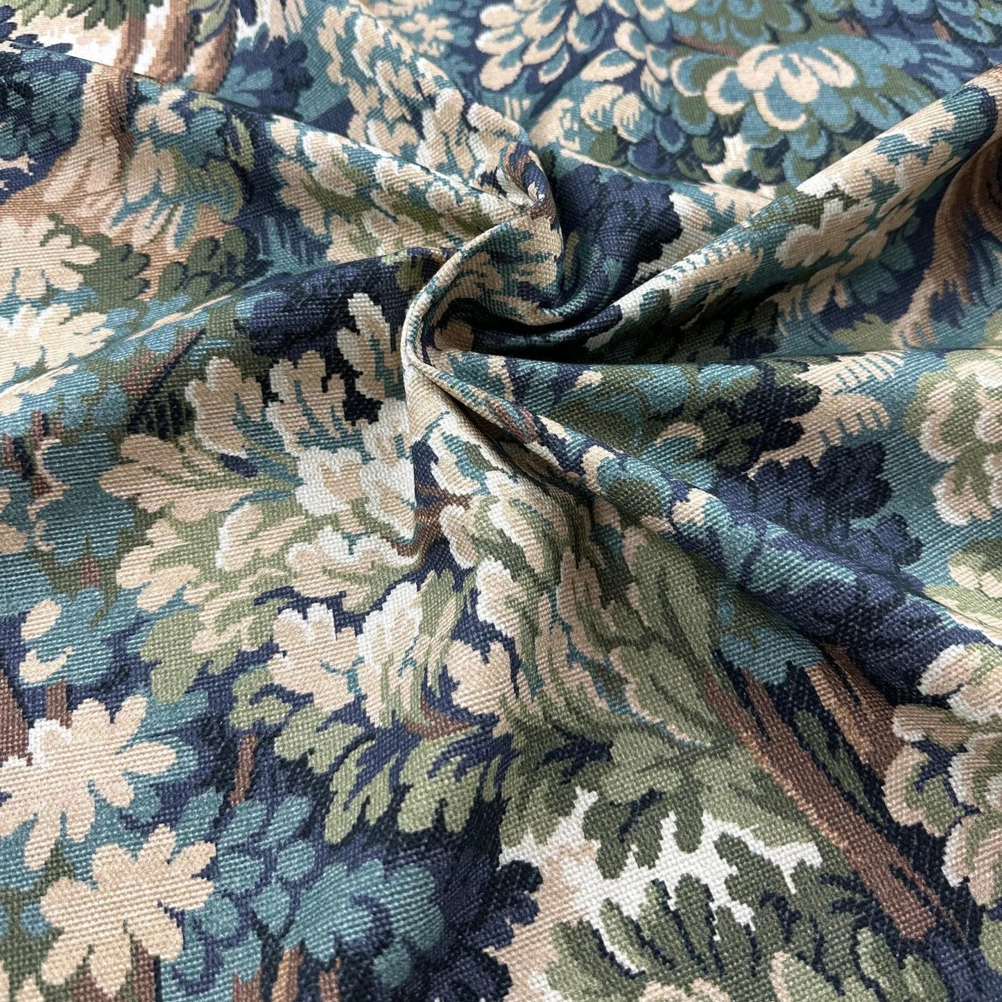 a close-up view of a fabric with a floral pattern in shades of blue, green, and white. The fabric appears to be made of a woven material, with a crinkled texture that suggests it is folded or rolled. The pattern is intricate and detailed, with a variety of colors and shapes that create a visually appealing design.