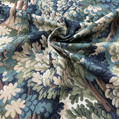 a close-up view of a fabric with a floral pattern in shades of blue, green, and white. The fabric appears to be made of a woven material, with a crinkled texture that suggests it is folded or rolled. The pattern is intricate and detailed, with a variety of colors and shapes that create a visually appealing design.