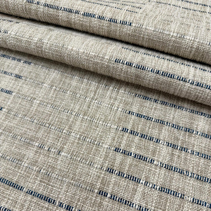 a close-up view of a fabric with a striped pattern in shades of beige and blue. The fabric appears to be folded or rolled, creating a layered effect.