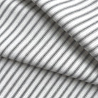 a close-up view of a fabric with a striped pattern in black and white. The fabric appears to be folded or crumpled, creating a textured and layered appearance.