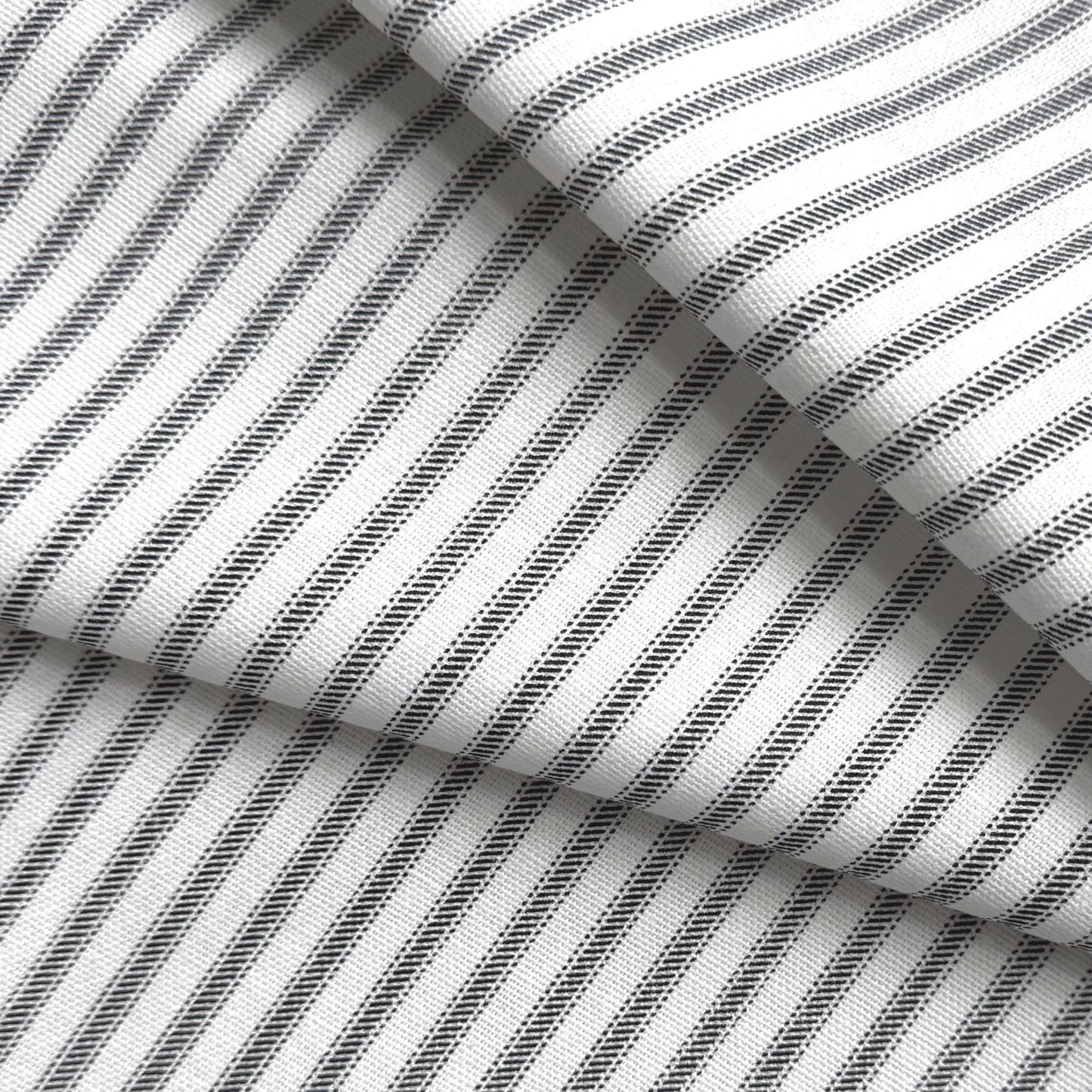 a close-up view of a fabric with a striped pattern in black and white. The fabric appears to be folded or crumpled, creating a textured and layered appearance.