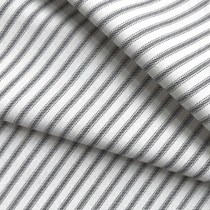 a close-up view of a fabric with a striped pattern in black and white. The fabric appears to be folded or crumpled, creating a textured and layered appearance.