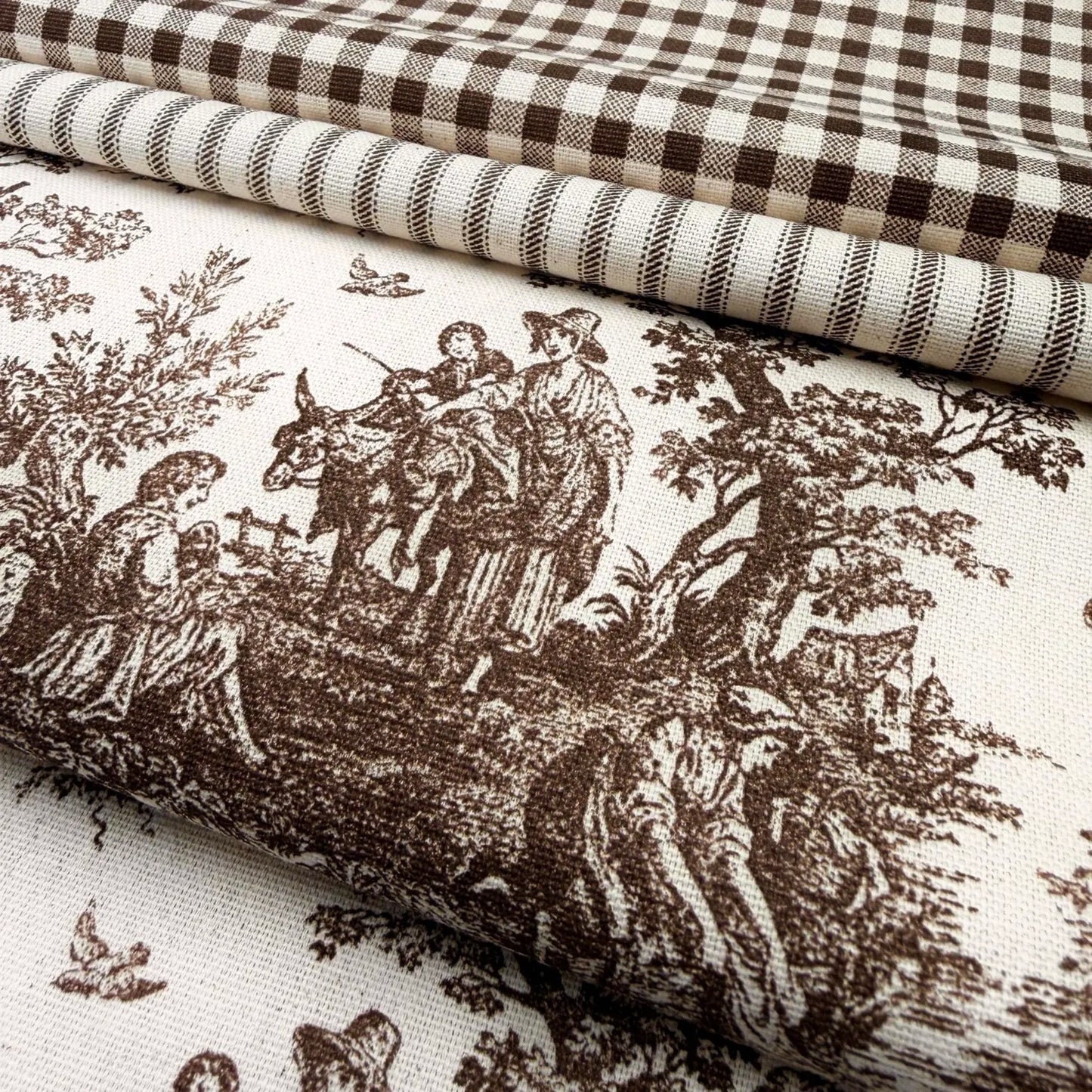 a close-up view of a fabric with a detailed brown and white pattern depicting a pastoral scene with people, animals, and trees.
