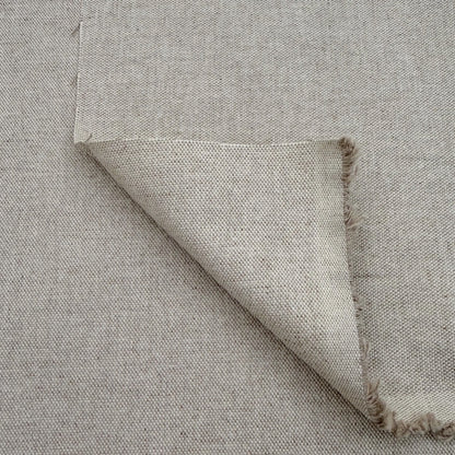a close-up view of a piece of fabric with a textured, woven appearance. The fabric appears to be made of a light-colored material, possibly linen or a similar type of textile. The fabric is folded over itself, creating a sense of depth and dimension in the image.