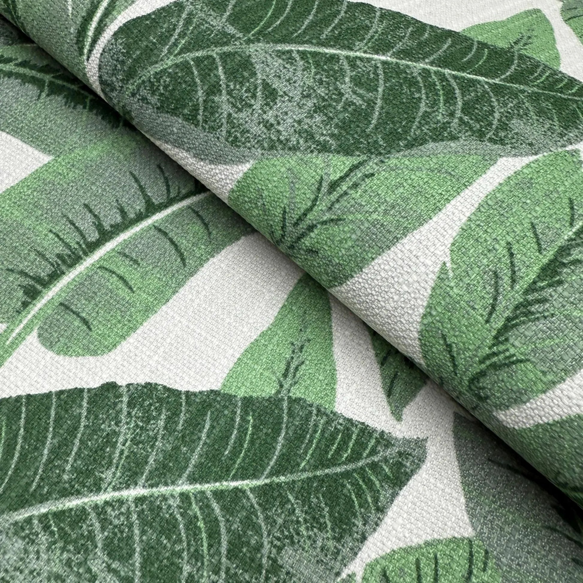 a close-up view of a fabric with a repeating pattern of green leaves. The leaves appear to be stylized and textured, creating a visually interesting and natural-looking design.