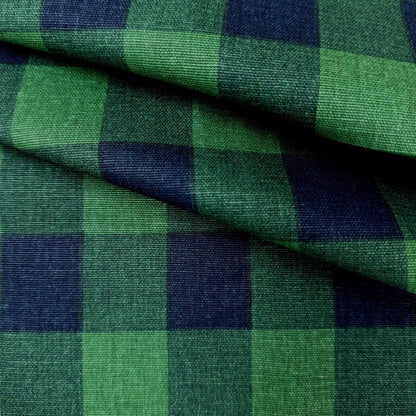 a close-up view of a fabric with a green and blue checkered pattern. The fabric appears to be folded or crumpled, creating a textured and visually interesting surface.