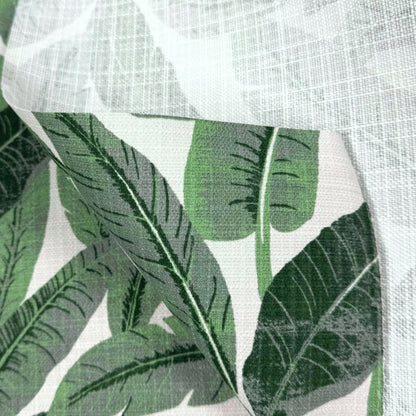a close-up view of a fabric with a repeating pattern of green leaves, likely palm leaves, against a white background.