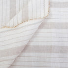 Taupe stripe linen fabric styled in folds, showing airy drape, breathable weave, and soft neutral tones. This striped fabric is ideal for farmhouse table décor, minimalist curtains, cottage-inspired napkins, and rustic DIY home projects. The natural linen texture and classic stripe design make it a versatile material for sewing projects that require elegance and durability, such as lightweight drapery, tablecloths, or soft furnishings.