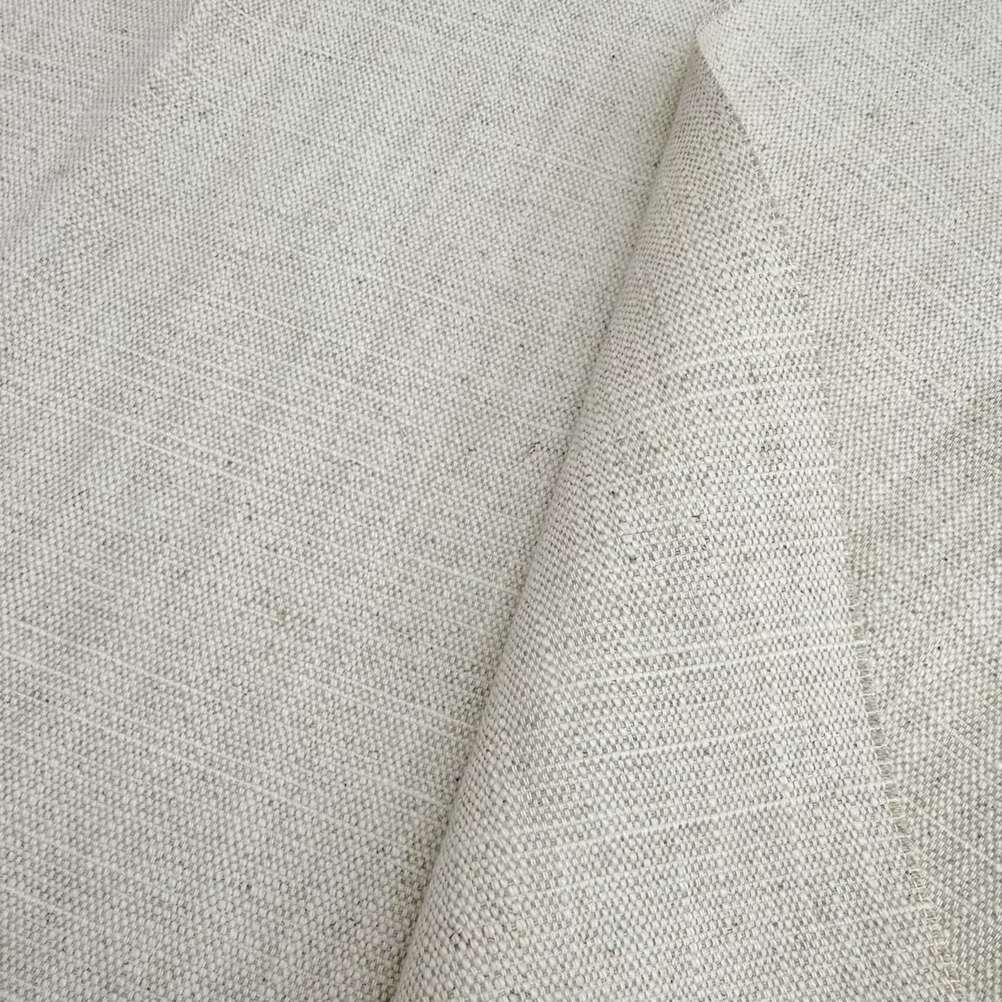 a close-up view of a fabric with a textured, woven appearance. The fabric appears to be made of a light-colored material, possibly linen or a similar type of textile. The image does not contain any text or other discernible objects or actions.
