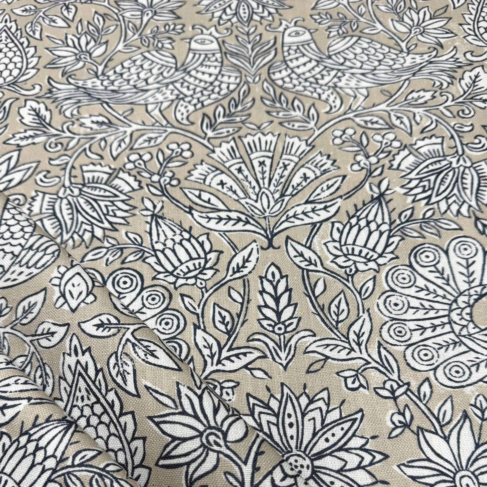 a close-up view of a fabric with a repeating floral pattern in shades of beige and black. The pattern consists of various flowers and leaves, creating a visually striking and intricate design. The image does not contain any text or other discernible objects or actions.