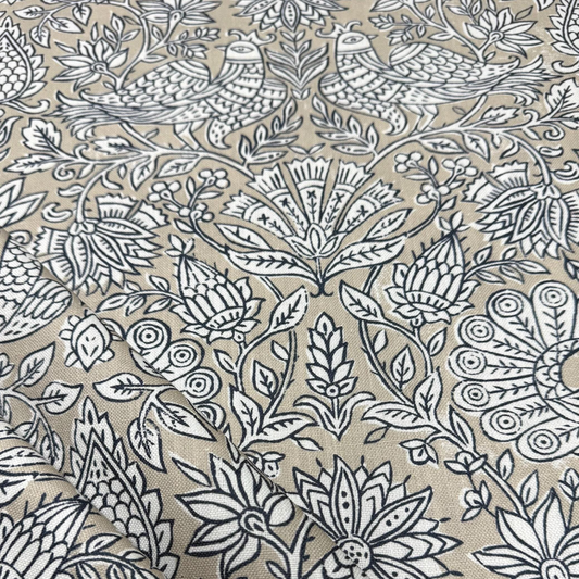a close-up view of a fabric with a repeating floral pattern in shades of beige and black. The pattern consists of various flowers and leaves, creating a visually striking and intricate design. The image does not contain any text or other discernible objects or actions.
