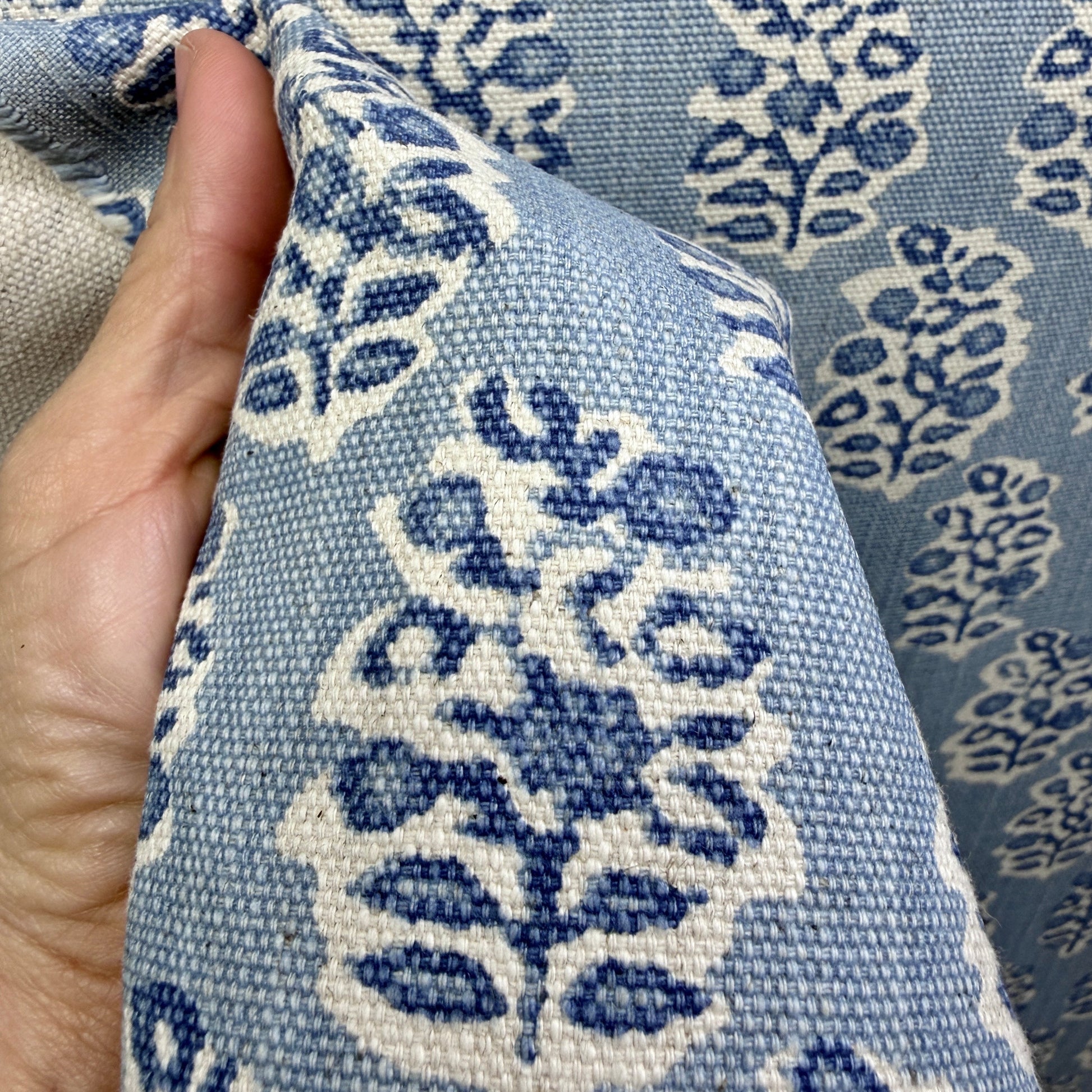 Close-up of blue and cream block print fabric held to highlight texture and weave detail