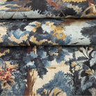 The image is a close-up of a fabric with a floral pattern, featuring a mix of blue, green, and brown colors.