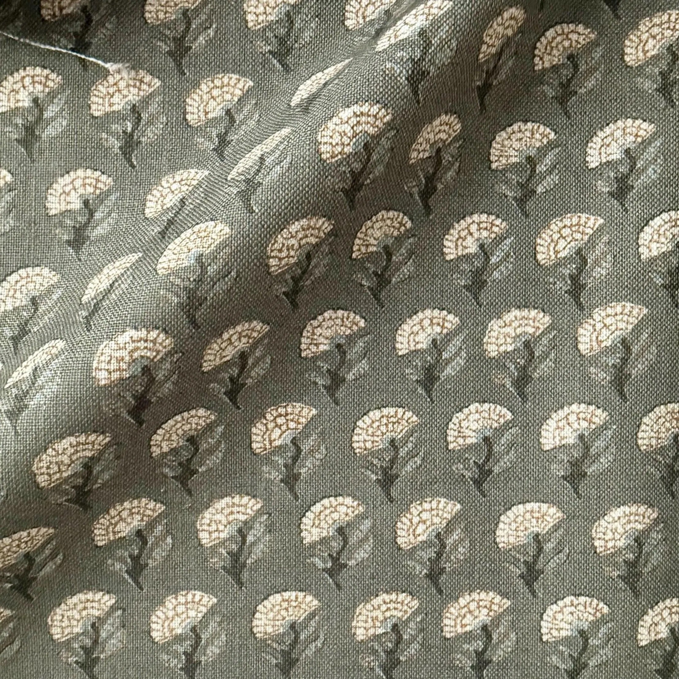 a close-up view of a fabric with a repeating pattern of white flowers or leaves on a dark background.