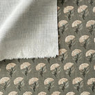 a close-up view of a fabric with a floral pattern, featuring a mix of white and gray colors. The fabric appears to be made of a soft, textured material, possibly cotton or linen. The pattern consists of repeating floral motifs, creating a visually appealing and intricate design.
