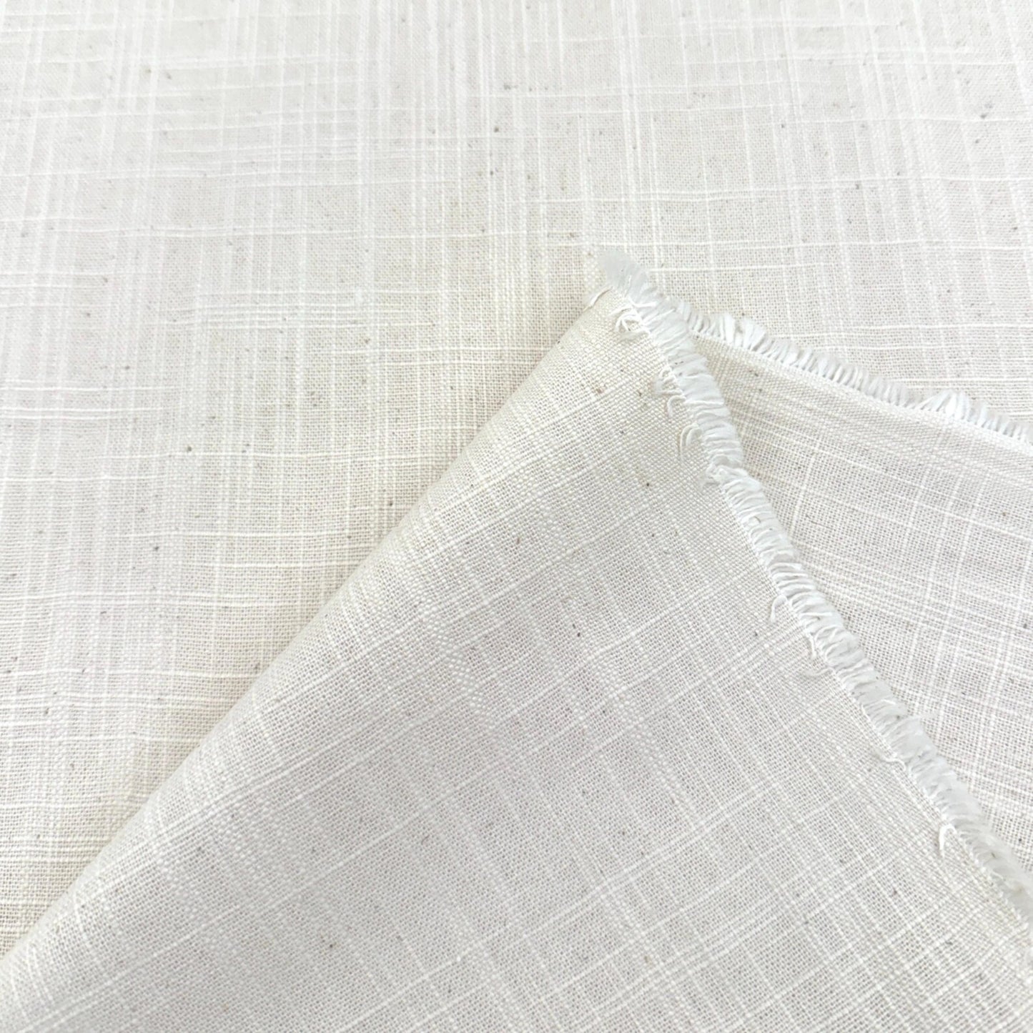 a close-up view of a white fabric with a criss-cross pattern, folded over itself to create a crease.