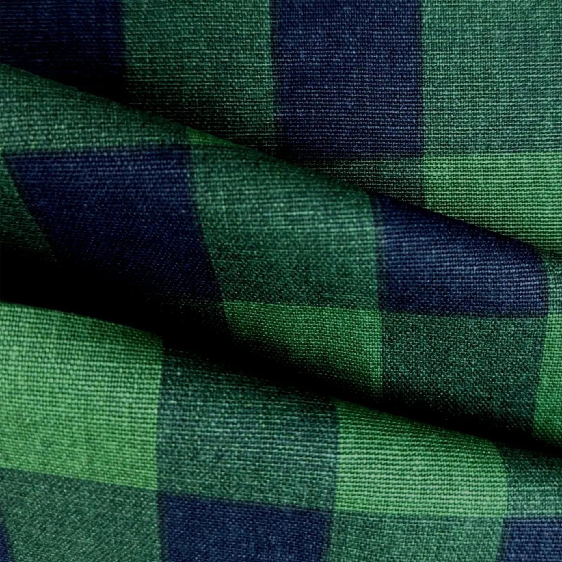 a close-up view of a fabric with a green and blue checkered pattern. The fabric appears to be made of a woven material, with a textured and wrinkled appearance.