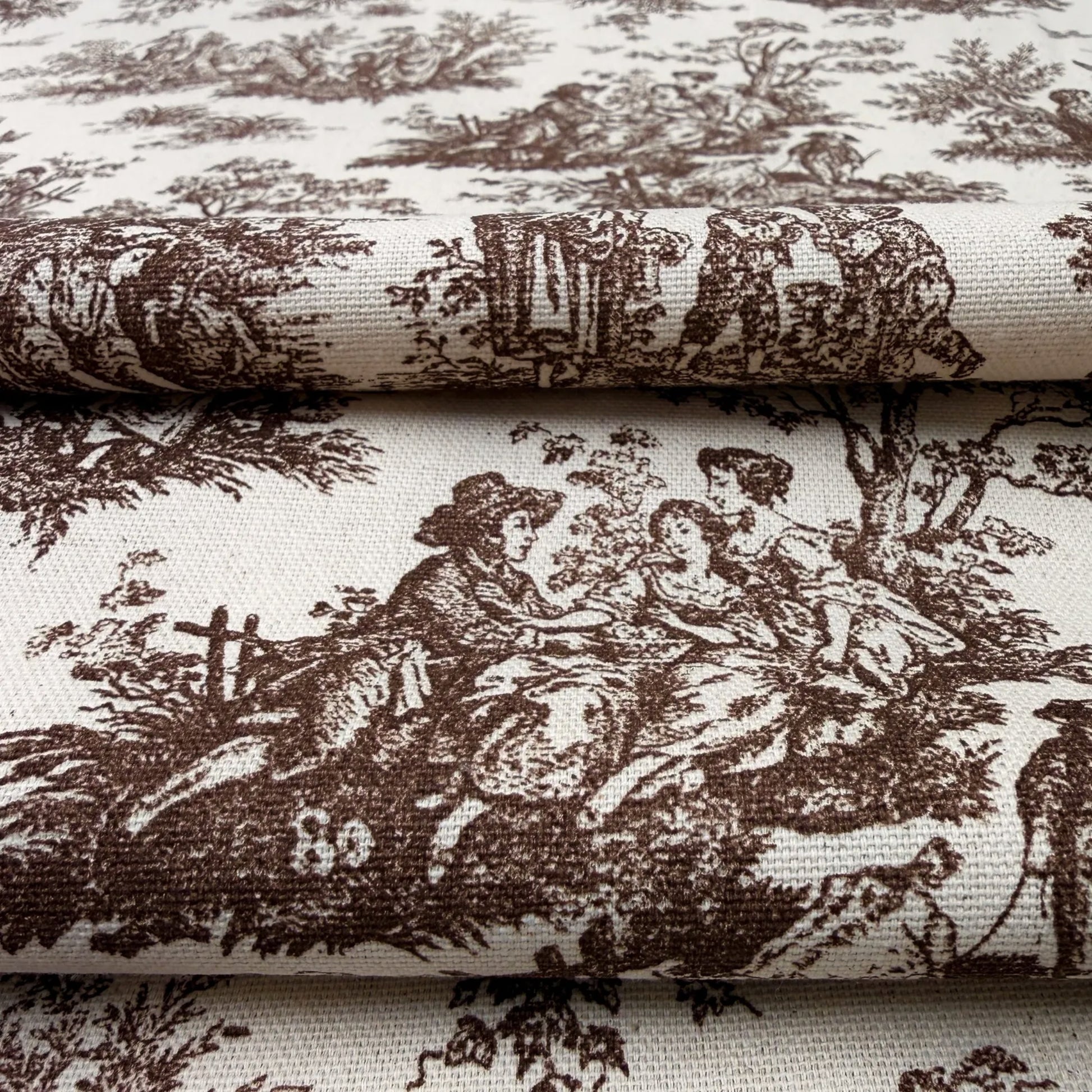 The image is a close-up of a fabric with a repeating brown and white pattern depicting a pastoral scene with people and animals.