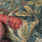 A close-up view of a fabric with a floral pattern, featuring a red flower and green leaves.