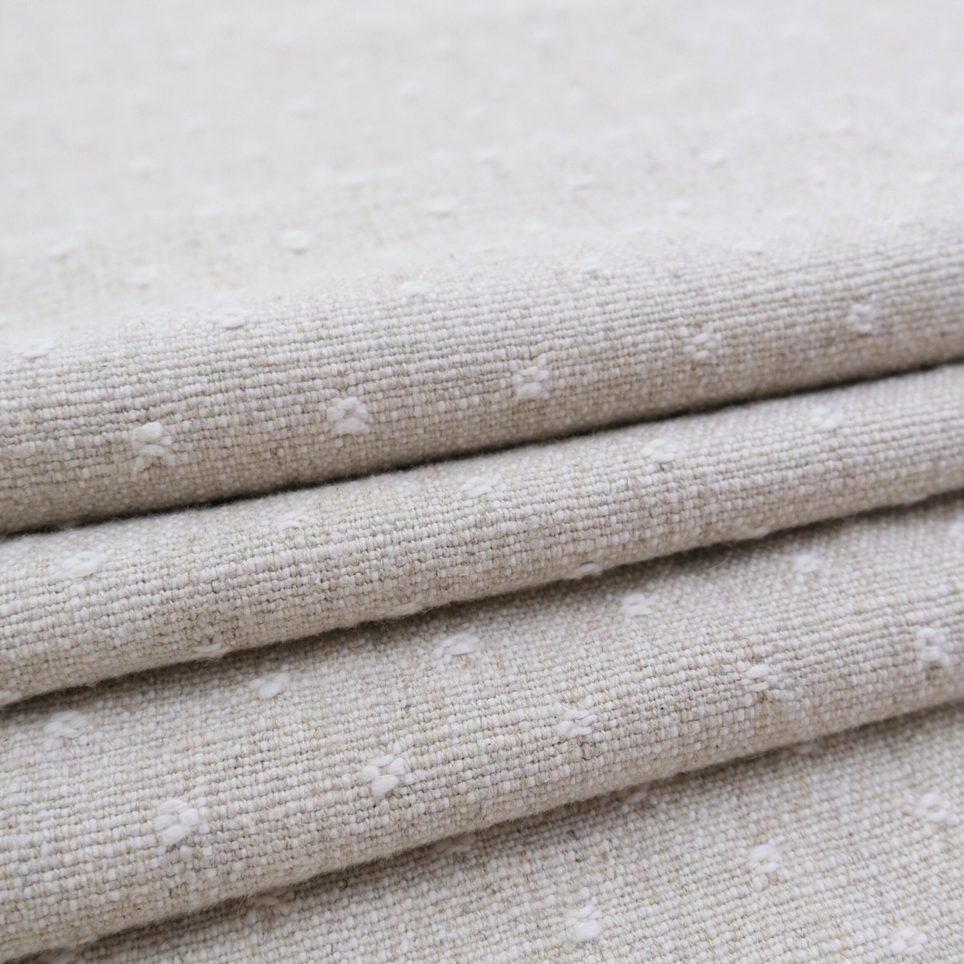 A close-up view of a folded fabric with a textured, beige-colored appearance.